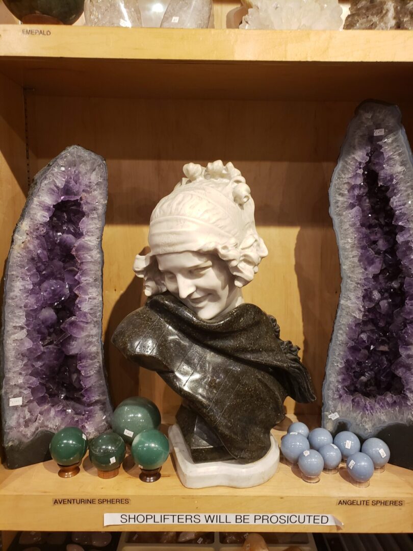 A statue of a woman with purple rocks and other items.